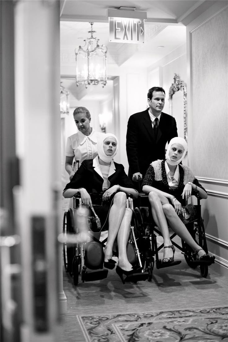 a group of people sitting in wheelchairs next to each other on a hallway way