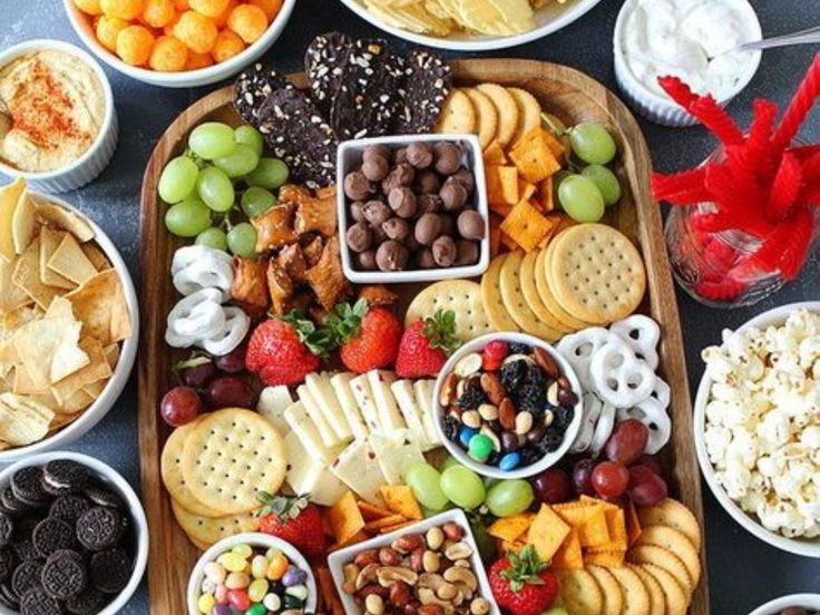 a platter filled with fruit, snacks and crackers on top of a table