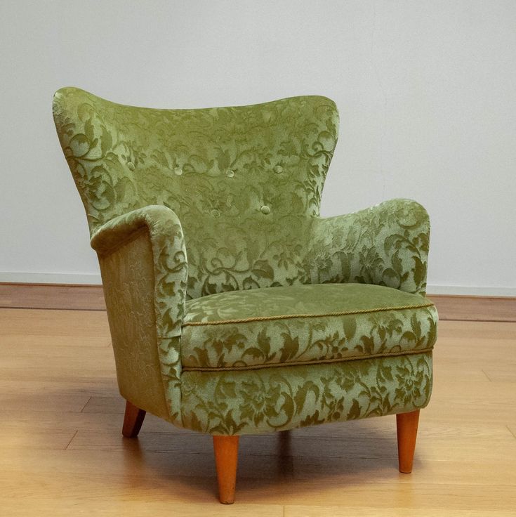 a green chair sitting on top of a hard wood floor next to a white wall