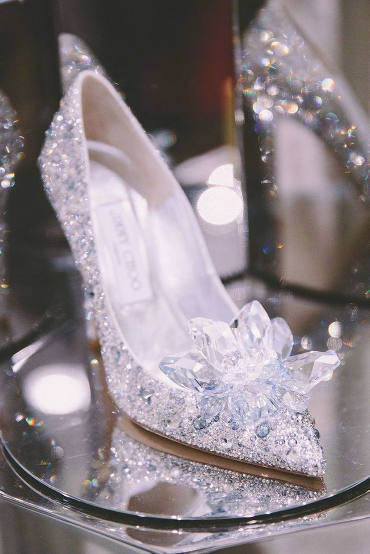 a pair of high heeled shoes sitting on top of a glass table next to a mirror