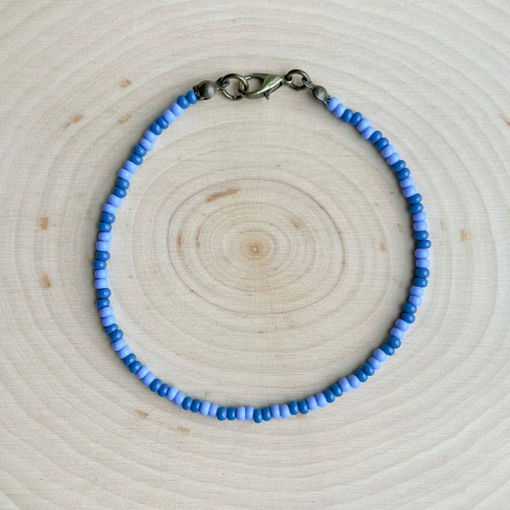 This is the Blueberry Beaded Anklet.  It is super cute, with lots of blueberry vibes!  This anklet is beautiful and elegant, yet also great for everyday casual wear. - It is fastened with antiqued bronze coated brass pieces, and is made with durable native glass seed beads. - My beads are always purchased here in Oklahoma from local native sellers. - It is 8.5" long with options for a 1" or 2" extender chain making it up to 10.5" long. *Note: Due to differences in device screens, the colors may Trendy Colorful Beaded Anklets As Gift, Blue Beaded Chain Bracelets For Beach, Trendy Anklets With Round Beads For Festivals, Adjustable Purple Beaded Bracelet With Beaded Chain, Adjustable Purple Beaded Chain Bracelets, Adjustable Purple Beaded Chain Bracelet, Casual Beaded Chain Bracelets For Summer, Handmade Blue Beaded Bracelets For Summer, Trendy Round Bead Anklets For Gift