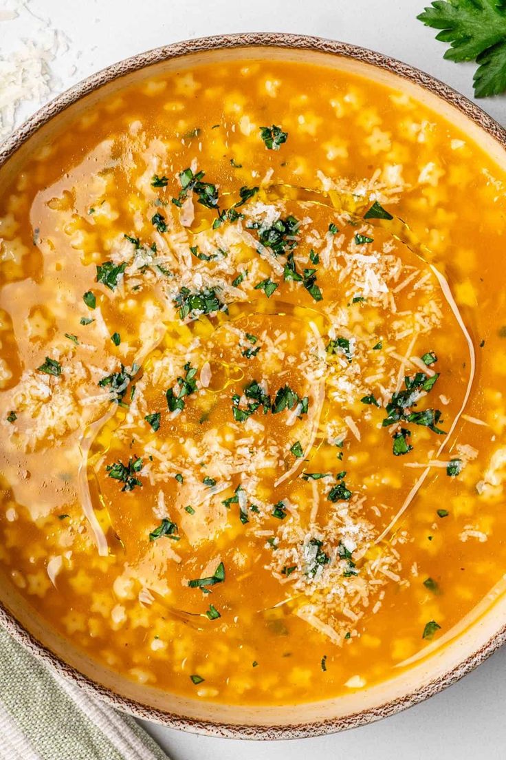 a bowl of soup with parmesan cheese on top and fresh parsley in the middle