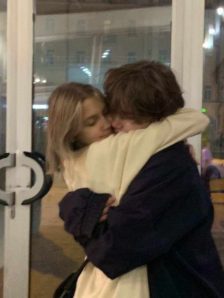 two people hugging each other in front of a glass door with the words love written on it