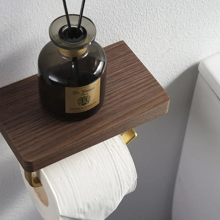 a brown and white toilet paper holder with a black bottle on it's lid