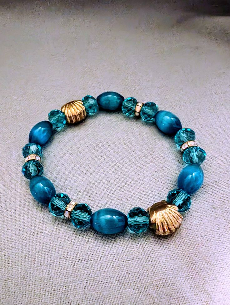 This pretty aqua and gold bracelet, is a stunning piece of handmade wrist decor that perfectly complements chic and feminine attire. This cute and stretchy charm is designed with the utmost care, making it an ideal fashion accessory for dressy special events or a thoughtful gift for your teen girlfriend. Its simple yet pretty design features aqua and gold beads, adding a touch of elegance and sparkle to her ensemble. Whether it's a bridesmaid present or a beaded party favor, this unique fine jew Elegant Handmade Turquoise Stretch Bracelet, Elegant Turquoise Stretch Bracelet As Gift, Elegant Turquoise Stretch Bracelet As A Gift, Turquoise Stretch Bangle Bracelet As Gift, Elegant Turquoise Beaded Stretch Bracelet, Turquoise Stretch Bangle Bracelet For Gift, Ocean-inspired Bracelets With Colorful Beads For Gifts, Elegant Turquoise Adjustable Charm Bracelet, Turquoise Ocean-inspired Bracelet For Summer