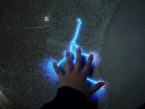 a person's hand is touching a blue lightening effect on the ground with their fingers