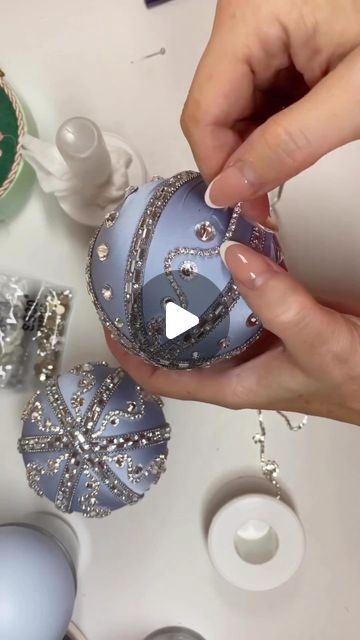 someone is decorating an ornament with beads and jewels on the table next to other ornaments