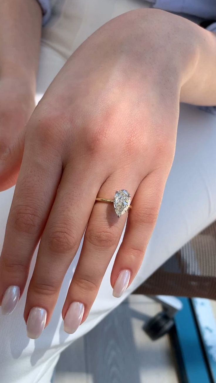 a close up of a person's hand with a diamond ring on their finger