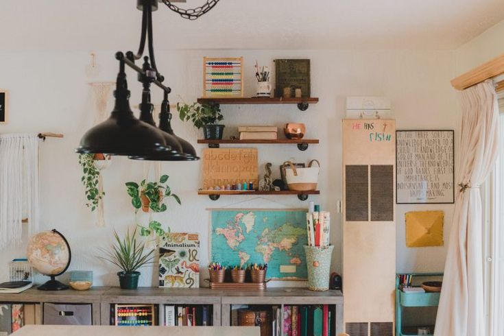 a dining room table with books and plants on the shelves above it, next to a window