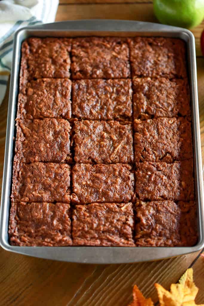 a pan filled with brownies sitting on top of a table next to an apple