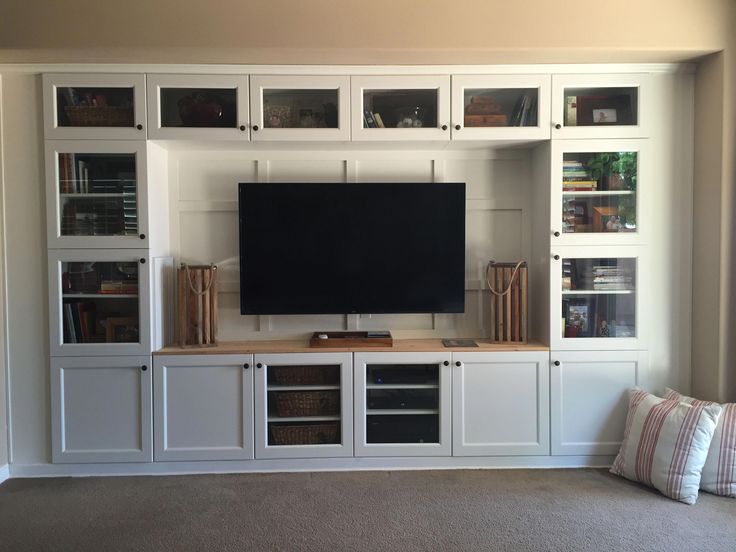 the entertainment center is built into the wall with glass doors and shelves on each side