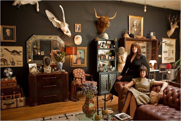 a woman sitting on a brown leather chair in front of a wall with deer heads