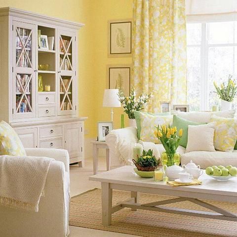 a living room filled with white furniture and yellow drapes on the window sill