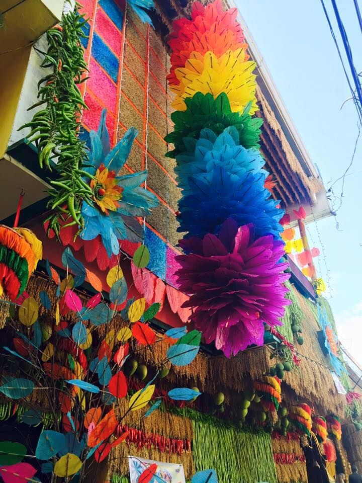 colorful paper flowers hanging from the side of a building