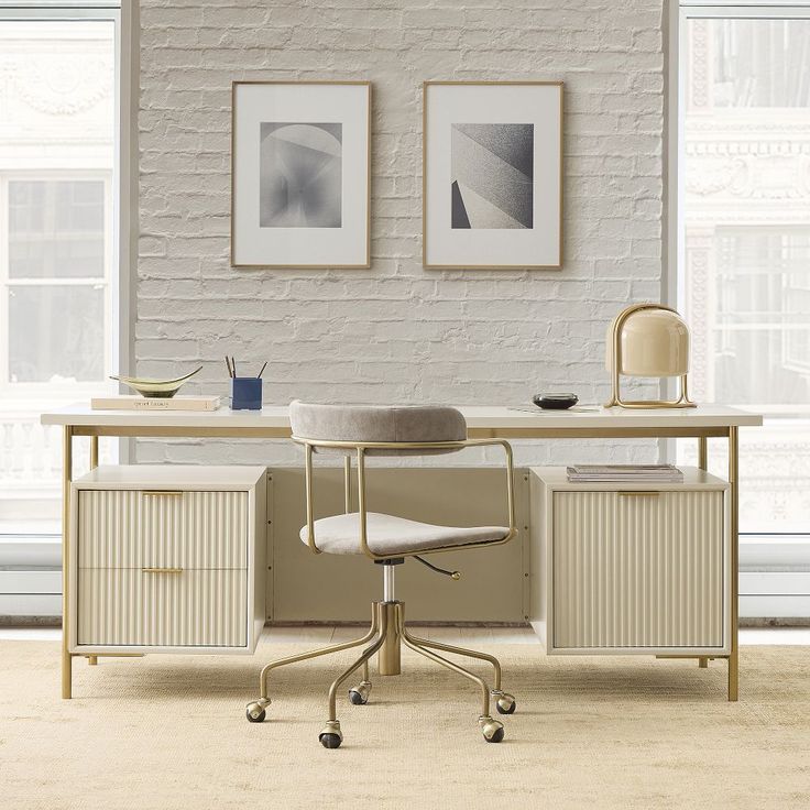 an office desk with two pictures on the wall above it and a chair in front of it