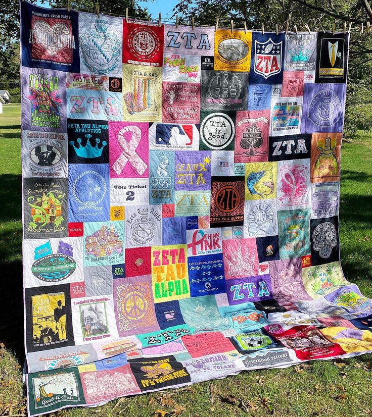 a quilt made with various t - shirts is displayed in the grass on a sunny day