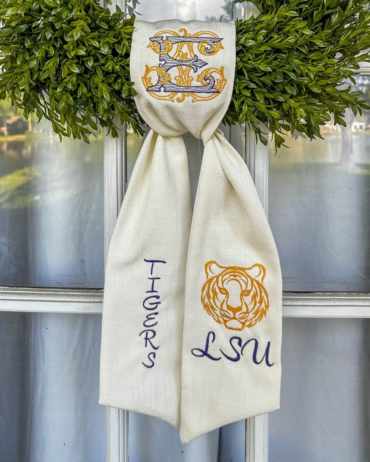 a white scarf hanging from the side of a window with an embroidered tiger on it