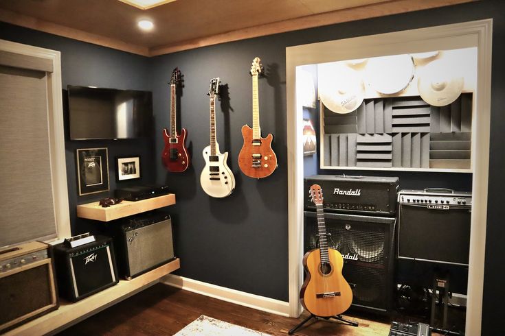 guitars and amps are lined up against the wall in this music studio room with black walls