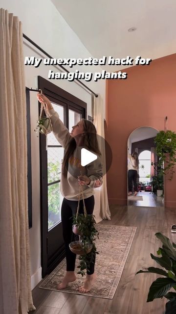 a woman is hanging plants in her living room with the words, my unexpected trick for hanging plants