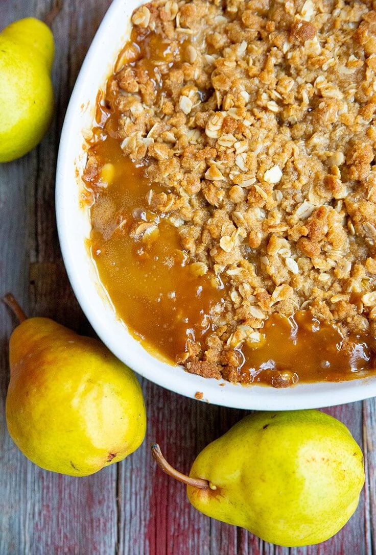 a bowl filled with granola sitting next to pears