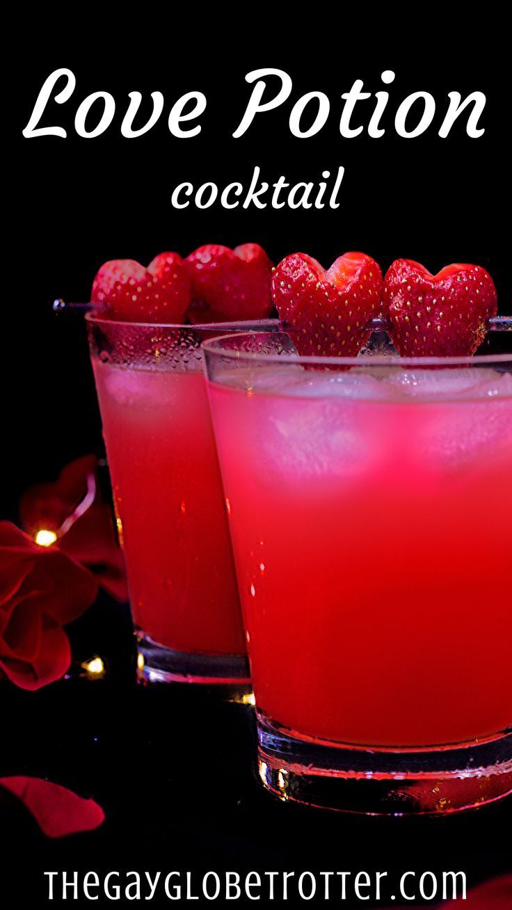 two glasses filled with red liquid and strawberries on the rim, sitting next to each other