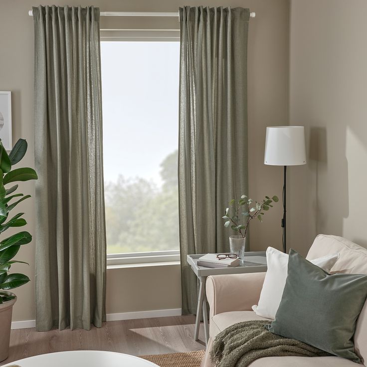 a living room filled with furniture and a large window covered in green curtained drapes