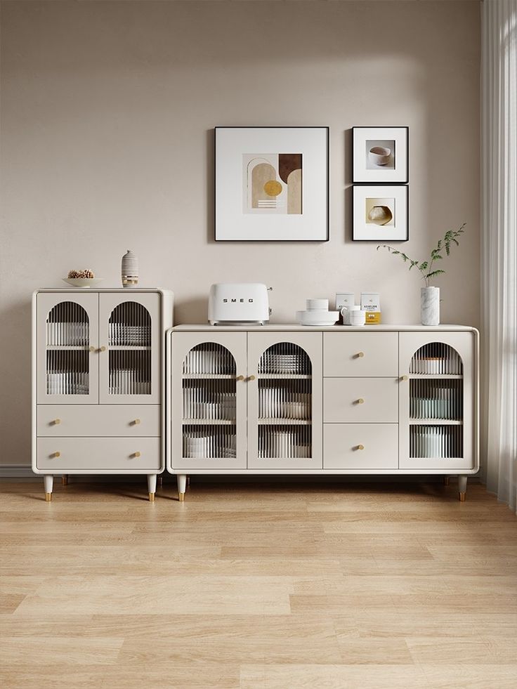 two white cabinets in a room with pictures on the wall