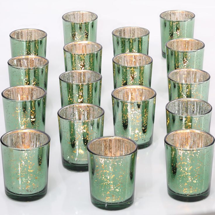 many green glass cups with gold speckles are lined up on a white surface