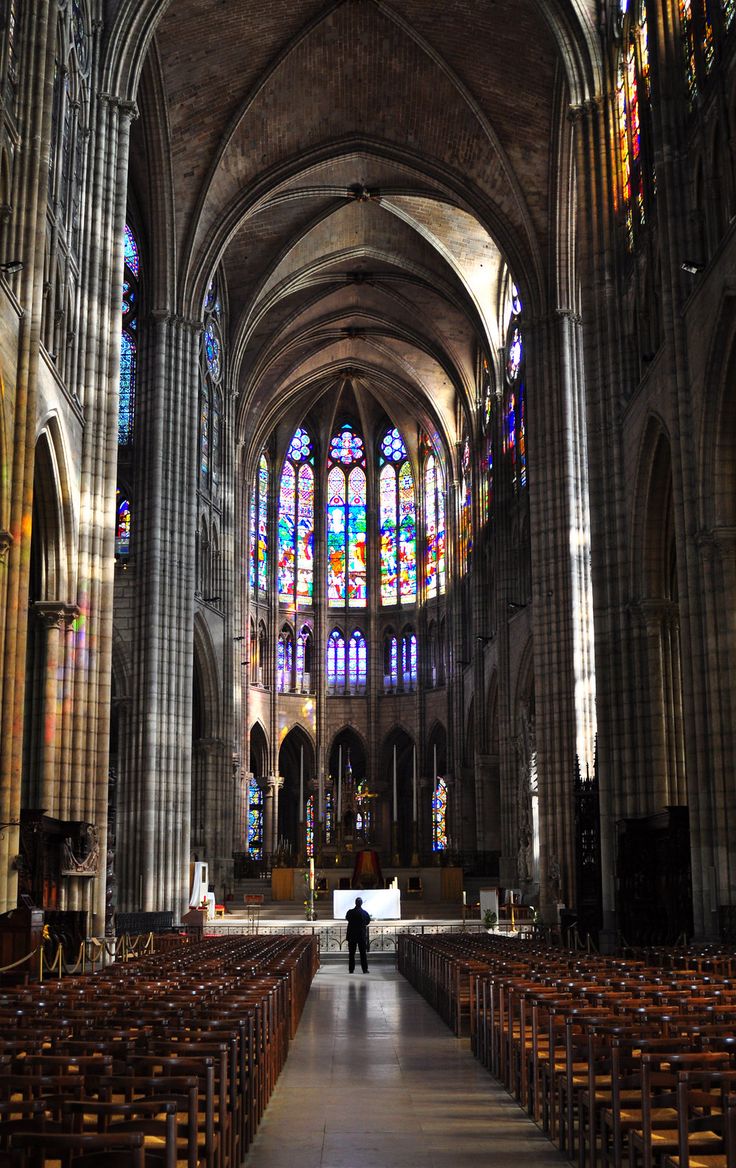 the inside of a cathedral with rows of pews and stained glass windows on both sides