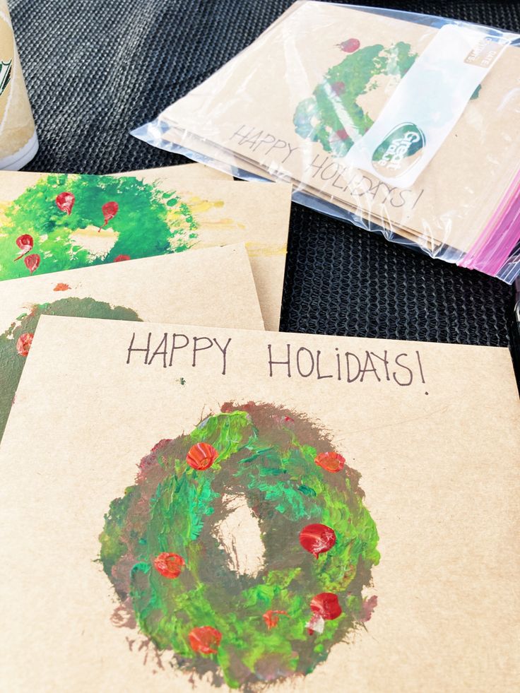 four christmas cards with the words happy holidays written on them are sitting on a table