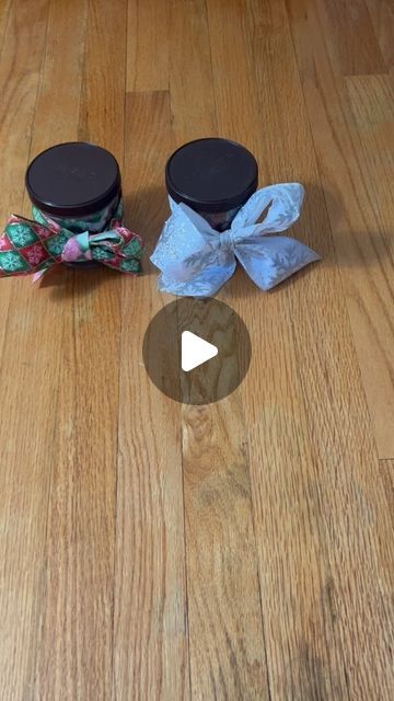 three small jars with bows on them sitting on the floor next to an empty container