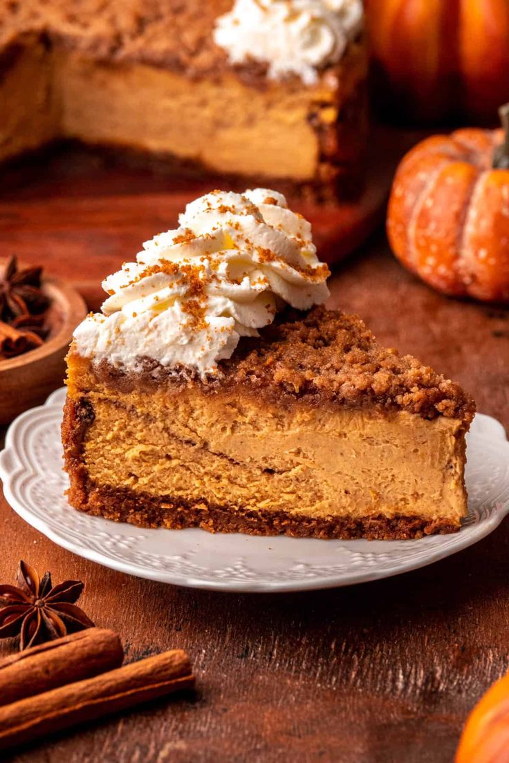 a slice of pumpkin pie on a white plate with whipped cream and cinnamon sprinkles