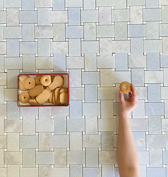 a hand is holding a cookie in front of a box of cookies on the floor