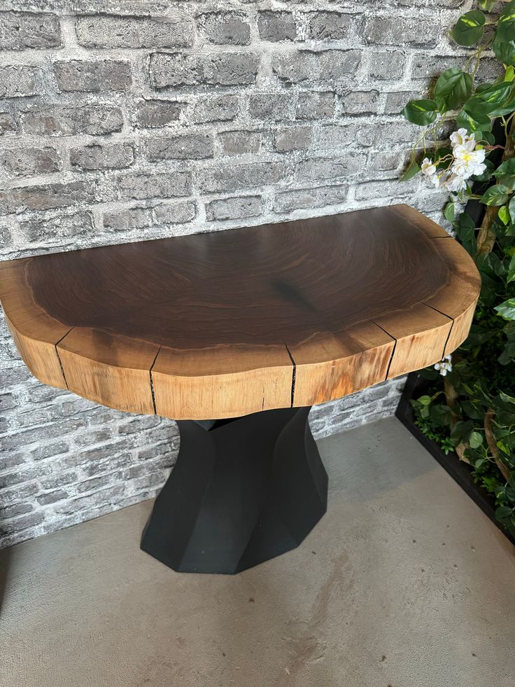 a wooden bench sitting on top of a cement floor next to a brick wall and green plants