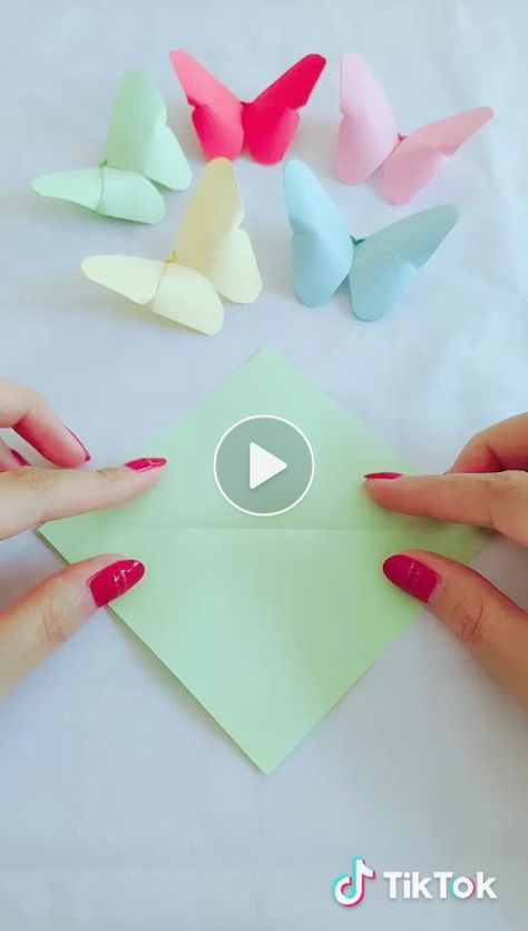 someone cutting out paper butterflies on top of a sheet of green paper with red and white nail polish