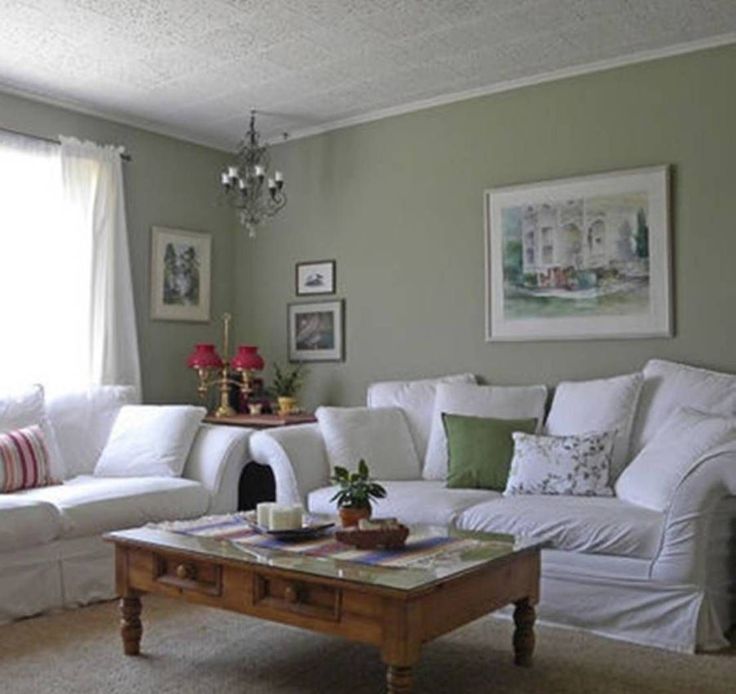 a living room with white furniture and green walls