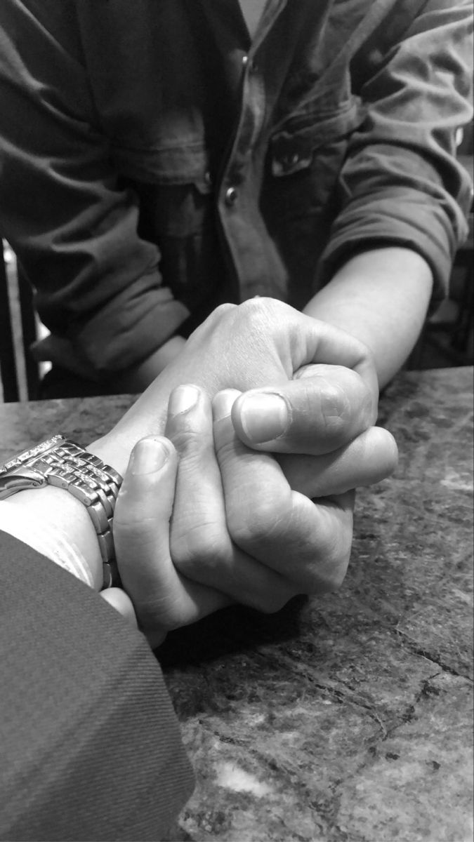 two people holding hands at a table