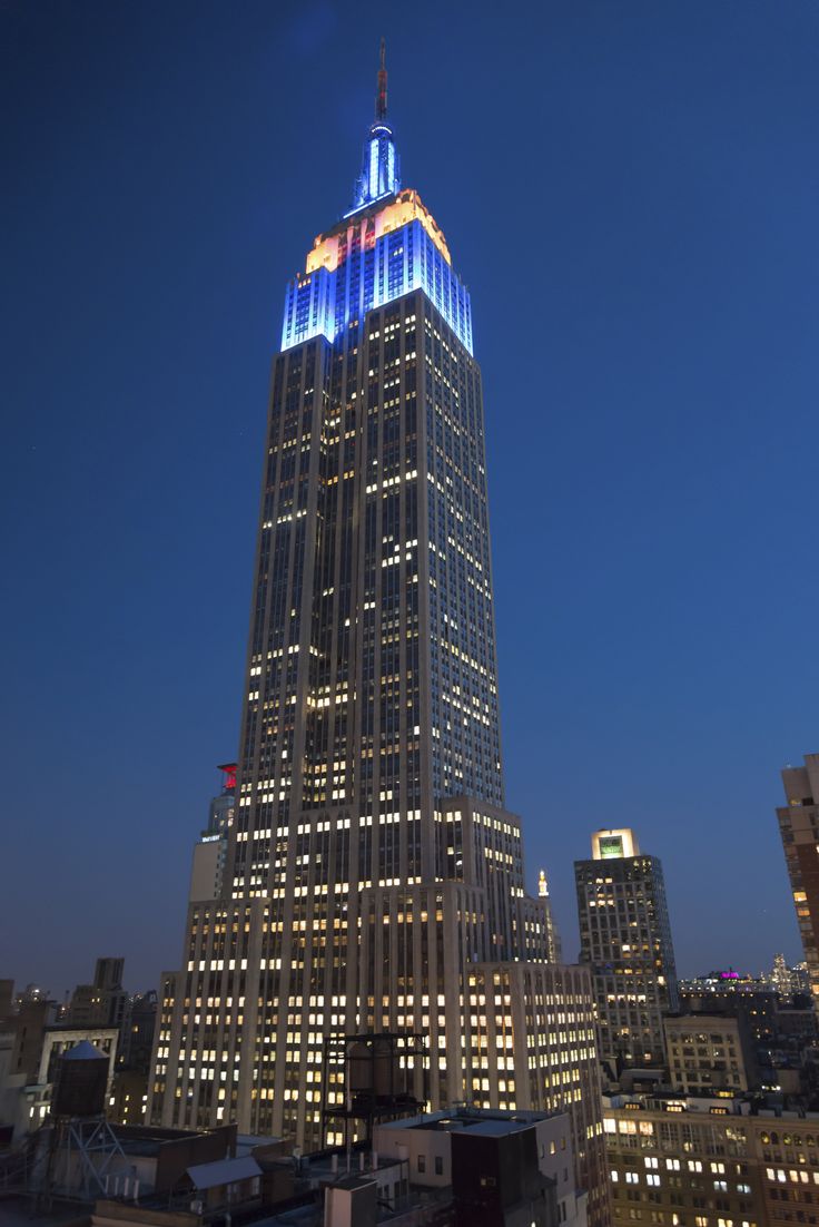 the empire building is lit up in blue and white for new york city's holiday season