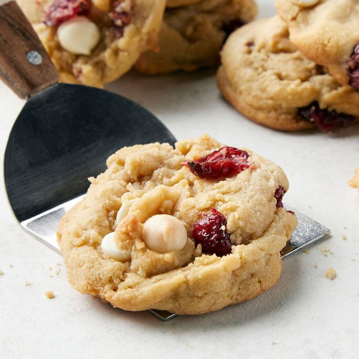 cookies with cranberries and white chocolate chips are on a cookie spatula next to other cookies