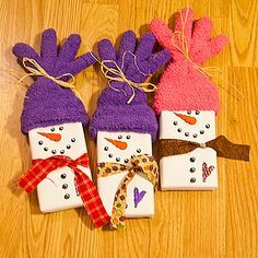 three snowmen made out of paper sitting on top of a wooden floor