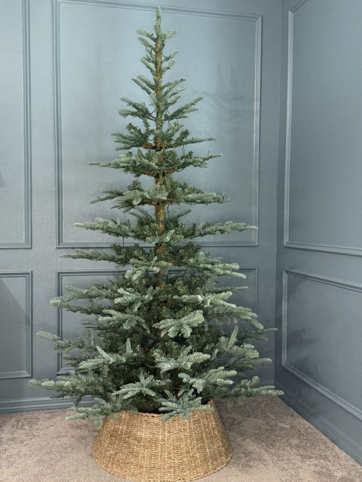 a small christmas tree in a basket on the floor