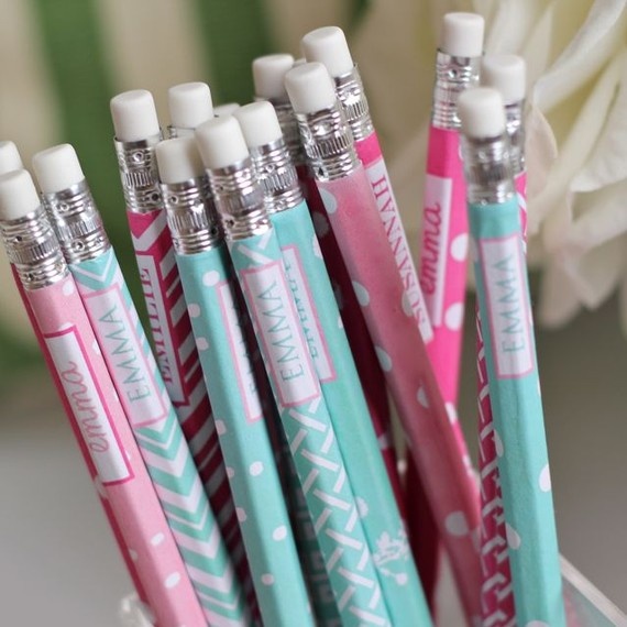 several pens are lined up in a glass container next to a white and pink flower