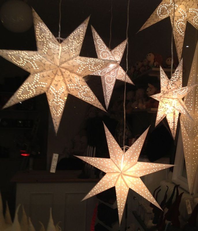 five white stars hanging from the ceiling in a room with other decorations and lights around them