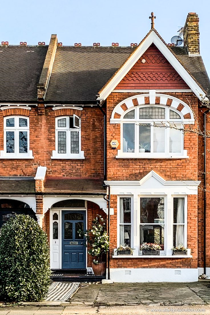 a red brick house with white trim on the front and side windows, along with a blue door