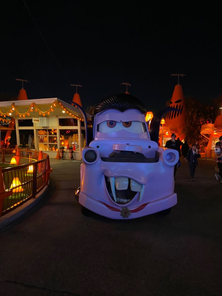 cars are parked in front of a building with lights and decorations on it at night