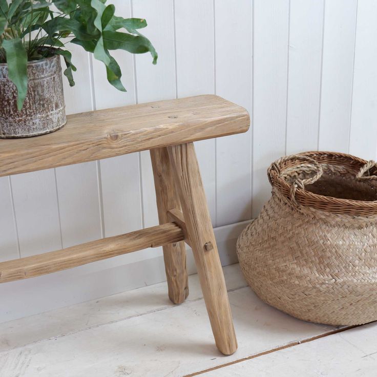 a small wooden bench next to a plant