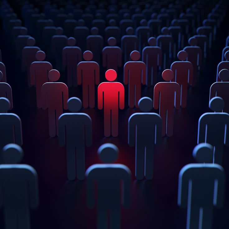 a group of people standing in the middle of a room with red light shining on them