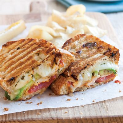 a sandwich cut in half sitting on top of a cutting board next to french fries