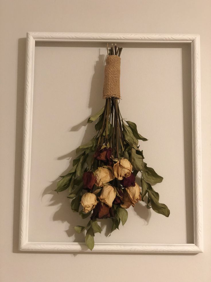 a white frame with flowers hanging on the wall