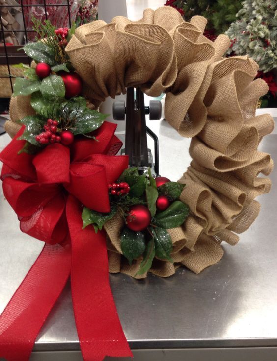 two wreaths with red bows on top of a metal counter next to each other